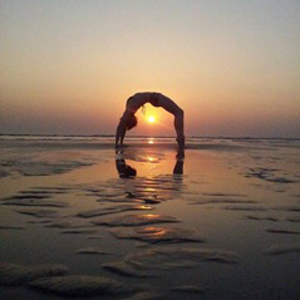 Kim Mackie in yoga pose on the beach at sunset