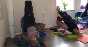 Women doing a yoga inversion on a chair in yoga studio